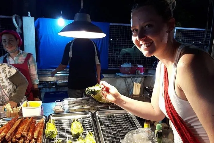 A guest tasting at a lit-up stall after dark